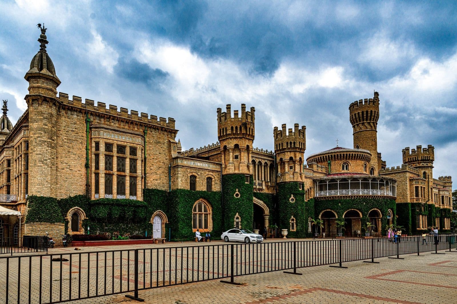 Bangalore Palace, a stone palace with turrets and ivy-covered walls, under a cloudy sky