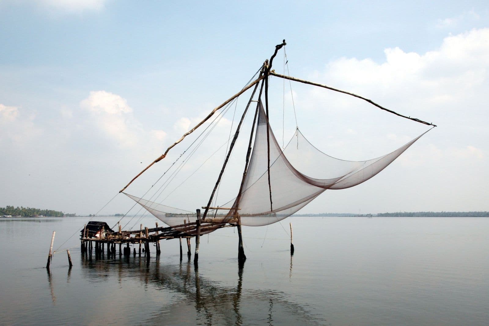 A Chinese fishing net raised above calm water on a wooden cantilever